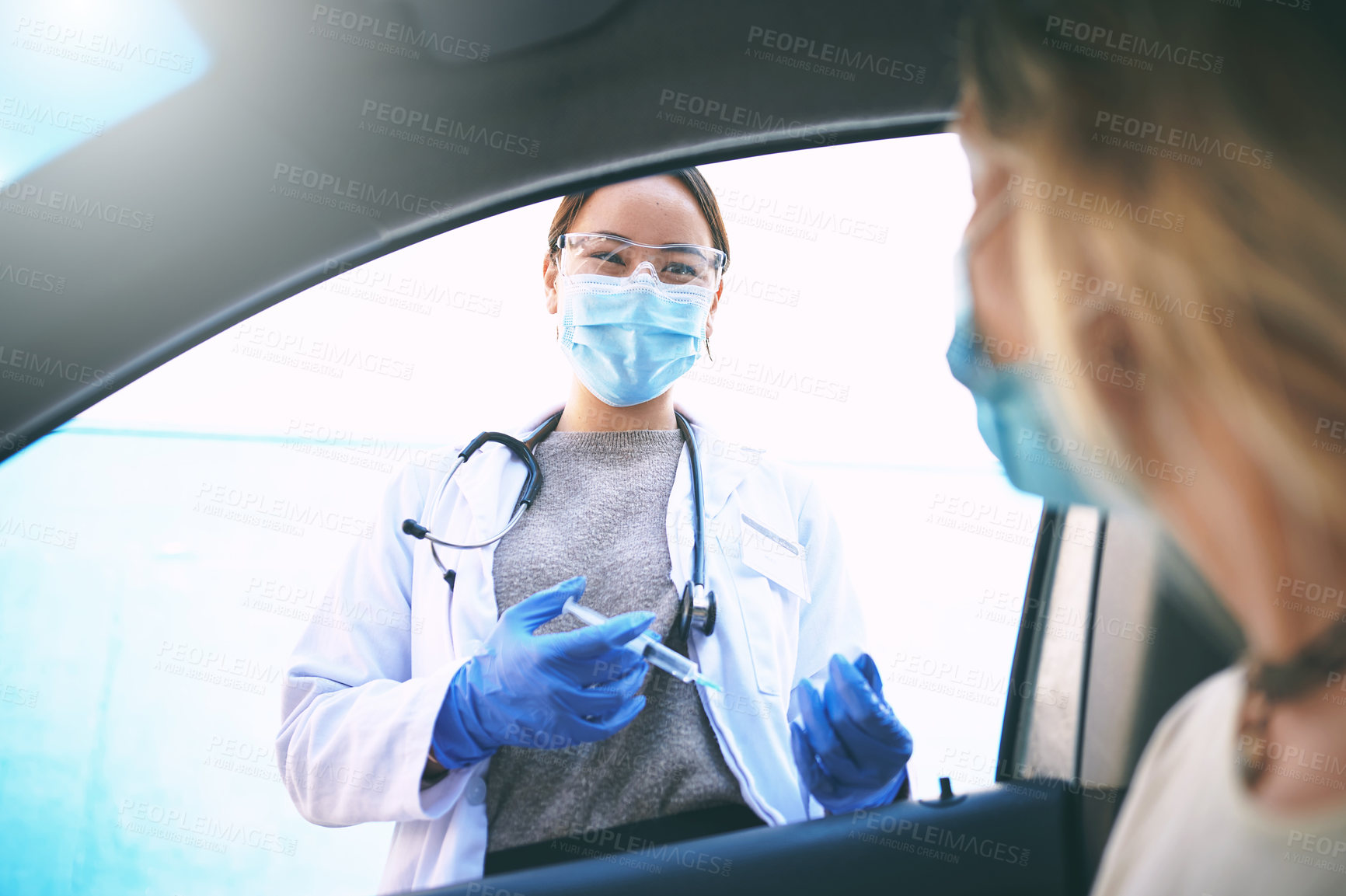 Buy stock photo Shot of a masked young doctor giving a patient an injection at a Covid-19 drive through testing centre