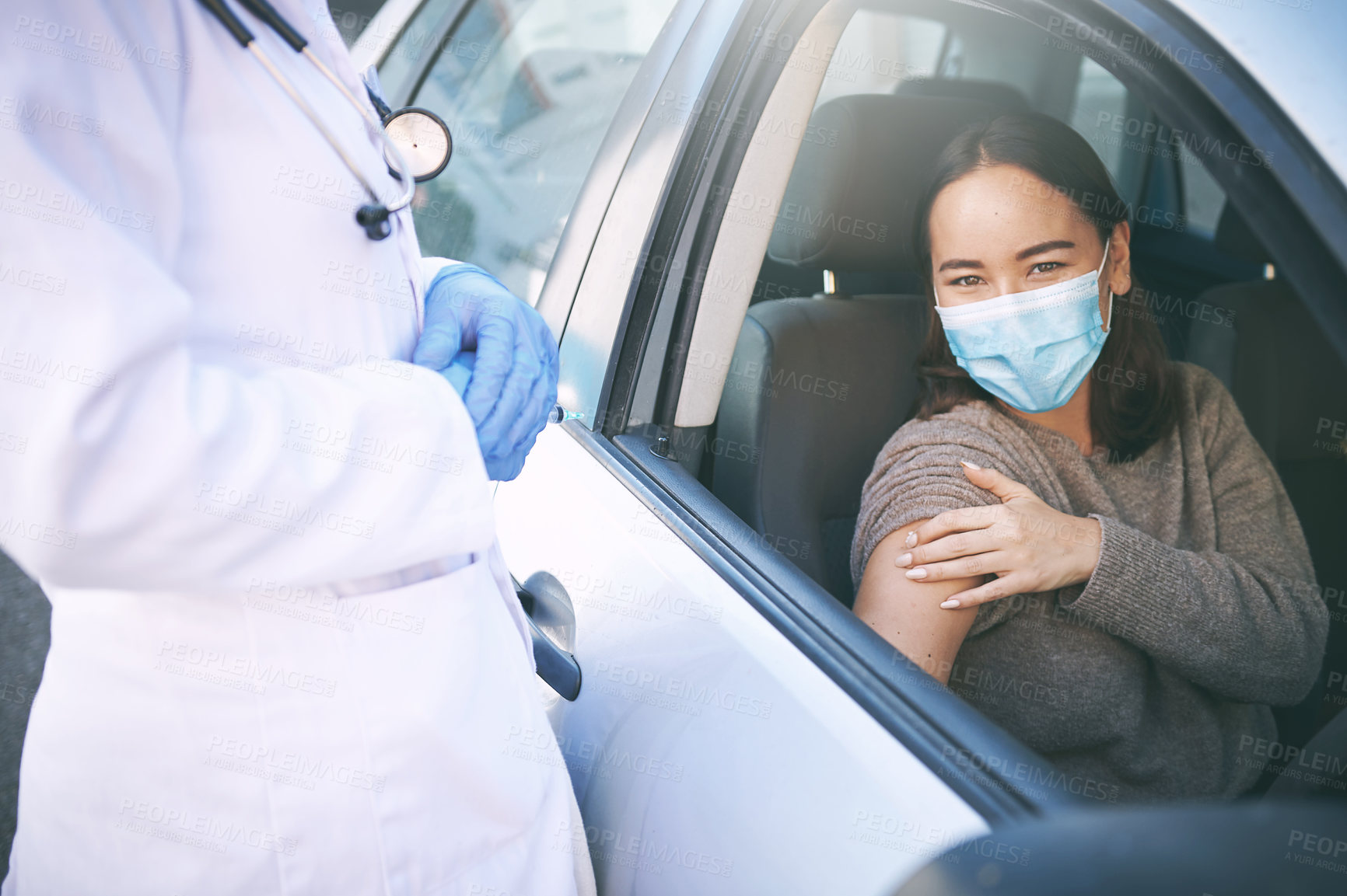 Buy stock photo Shot of a masked young woman receiving an injection at a Covid-19 drive through testing centre