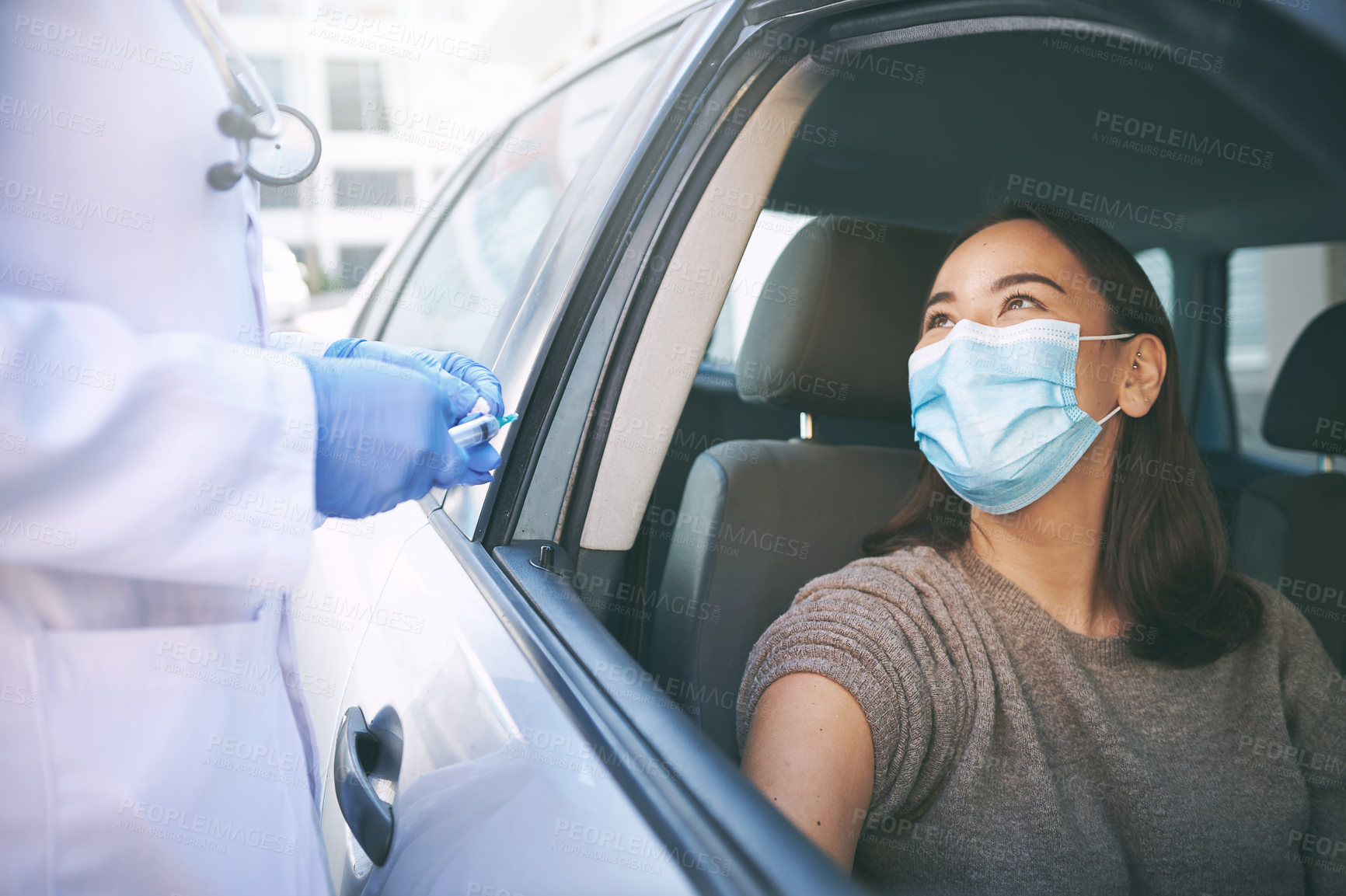 Buy stock photo Shot of a masked young woman receiving an injection at a Covid-19 drive through testing centre