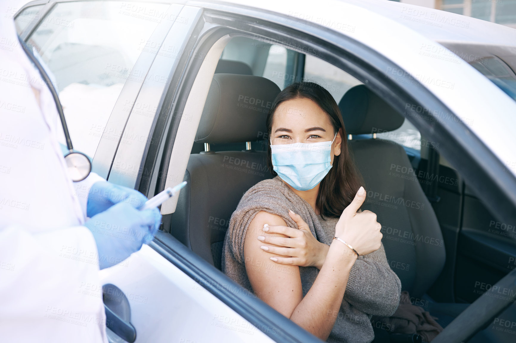 Buy stock photo Shot of a masked young woman receiving an injection at a Covid-19 drive through testing centre