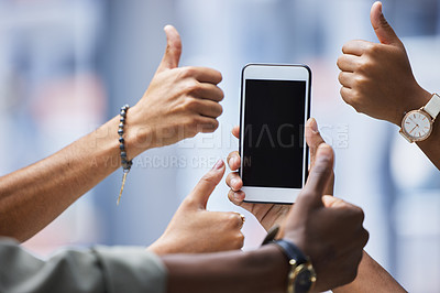 Buy stock photo Closeup shot of a group of unrecognisable businesspeople showing thumbs up around a cellphone with a blank screen
