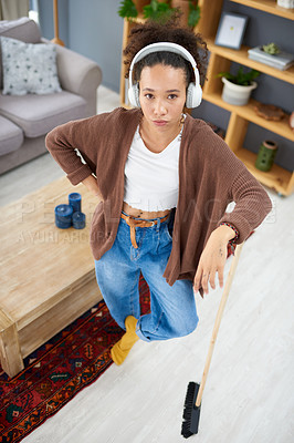 Buy stock photo Shot of a woman wearing headphones while busy cleaning at home