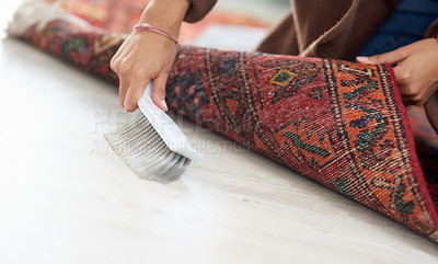 Buy stock photo Cropped shot of an unrecognizable woman sweeping under the carpet at home