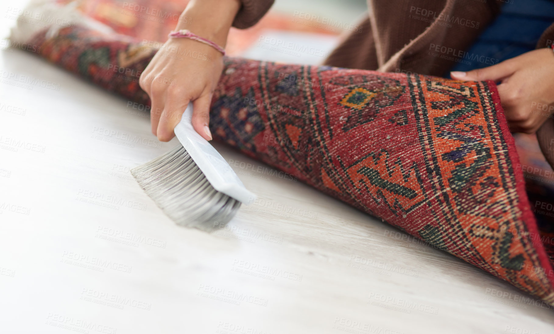 Buy stock photo Cropped shot of an unrecognizable woman sweeping under the carpet at home