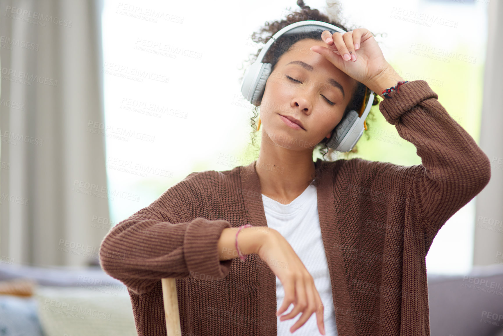 Buy stock photo Shot of a woman wearing headphones and looking exhausted after cleaning her house