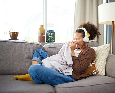 Buy stock photo Woman, clean laundry smell and headphones for music on sofa, comfort and calm with housekeeping. Relax in living room for fresh clothes, scent or fragrance with listening to radio or podcast at home