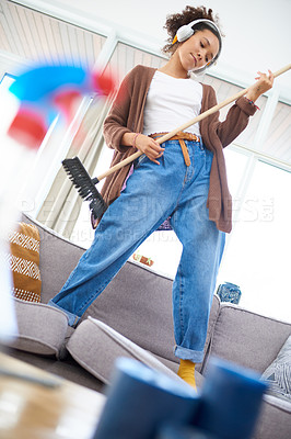 Buy stock photo Shot of a playful woman wearing headphones while cleaning at home