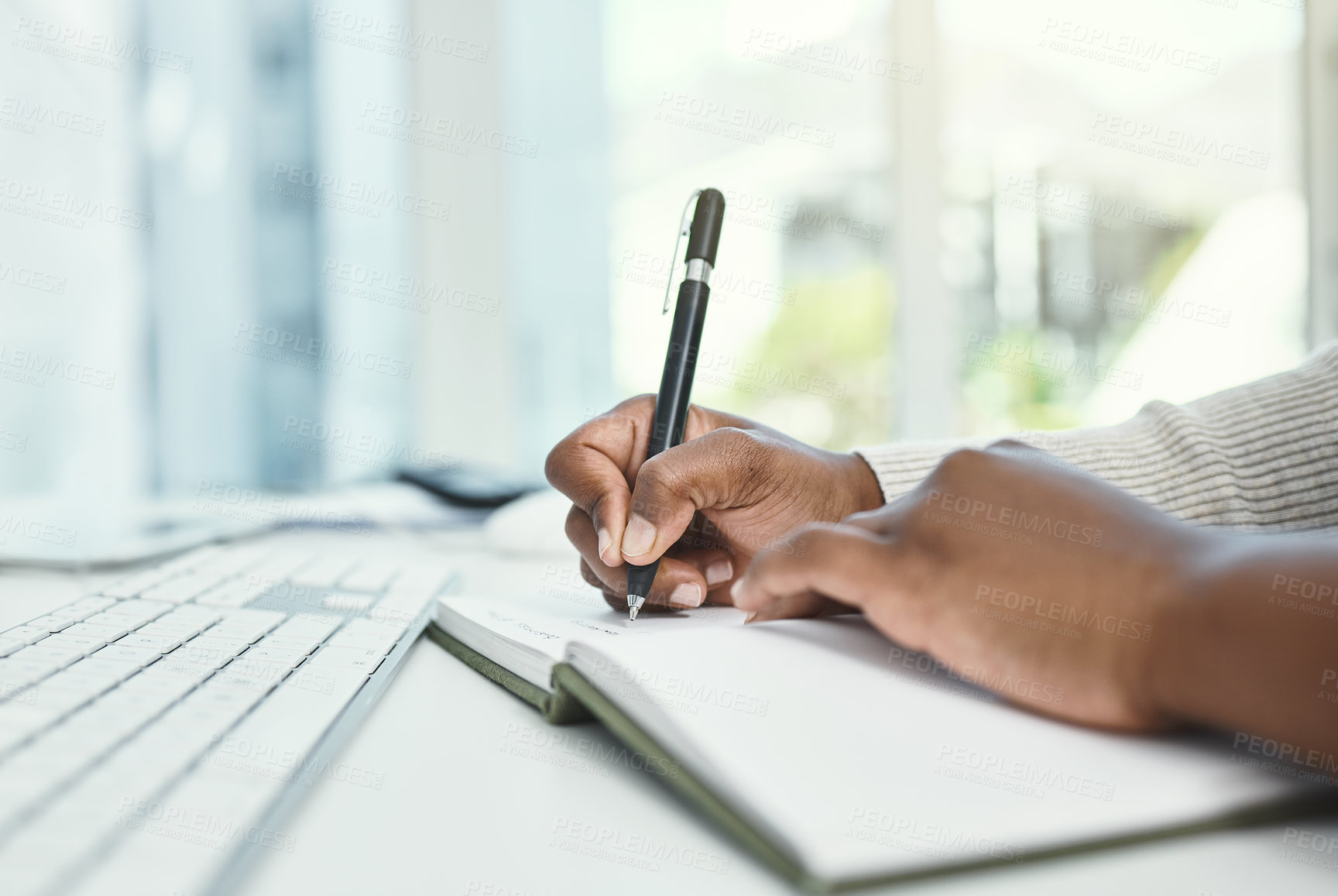 Buy stock photo Cropped shot of an unrecognizable businesswoman writing in her notebook while sitting at her desk