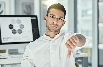 Buy stock photo Shot of a businessman showing thumbs down while sitting in a modern office