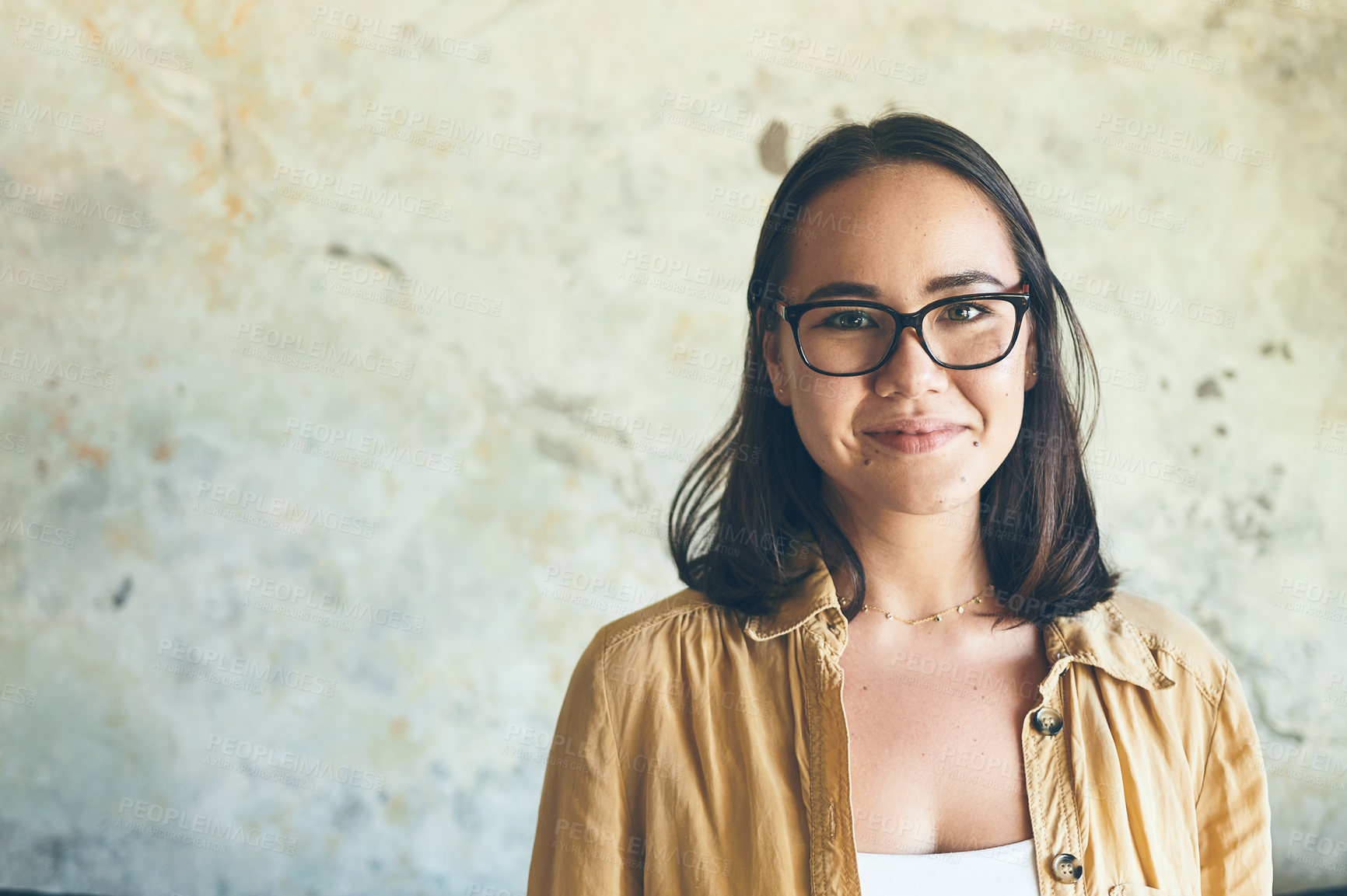 Buy stock photo Portrait of a confident young woman standing against a wall