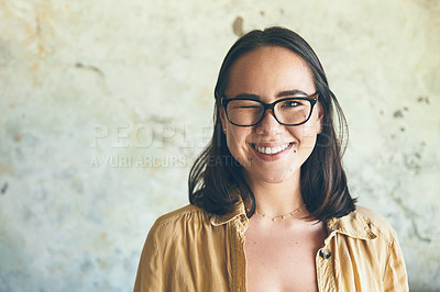 Buy stock photo Portrait of a young woman winking while standing against a wall
