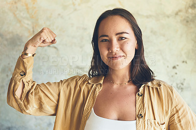 Buy stock photo Portrait of a young woman flexing her biceps against a wall