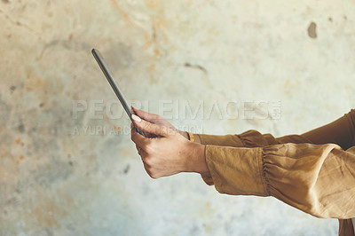 Buy stock photo Closeup shot of an unrecognisable woman using a digital tablet against a wall