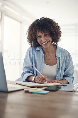 Buy stock photo Shot of an attractive young woman sitting alone in her home and writing in a notebook during the day