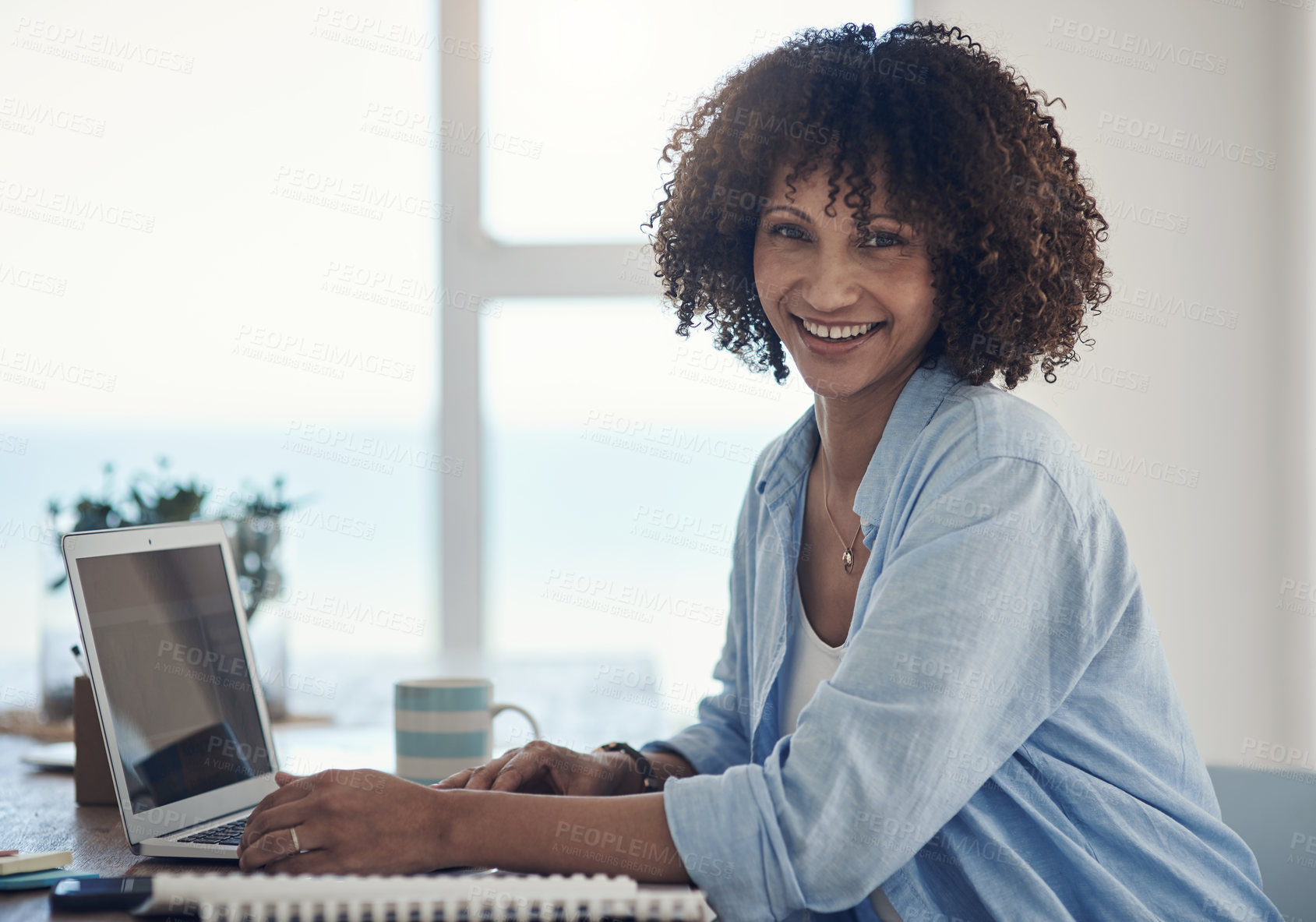 Buy stock photo Shot of an attractive young woman sitting alone at home and using her laptop