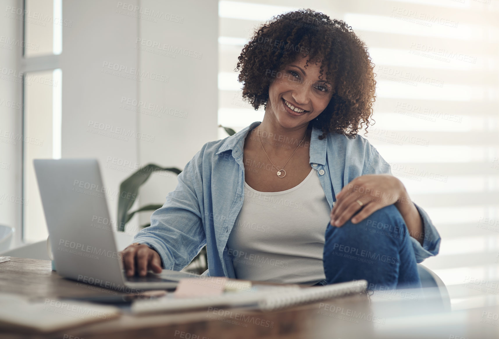 Buy stock photo Shot of an attractive young woman sitting alone at home and using her laptop