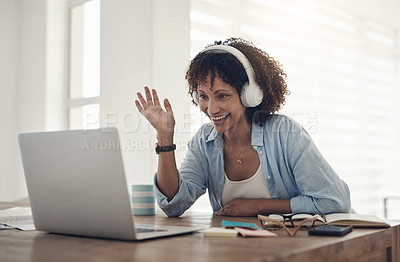 Buy stock photo Shot of an attractive young woman sitting at home and wearing headphones while using her laptop for a video chat