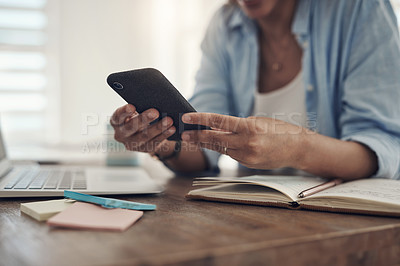 Buy stock photo Cropped shot of an unrecognizable woman sitting alone at home and using her cellphone