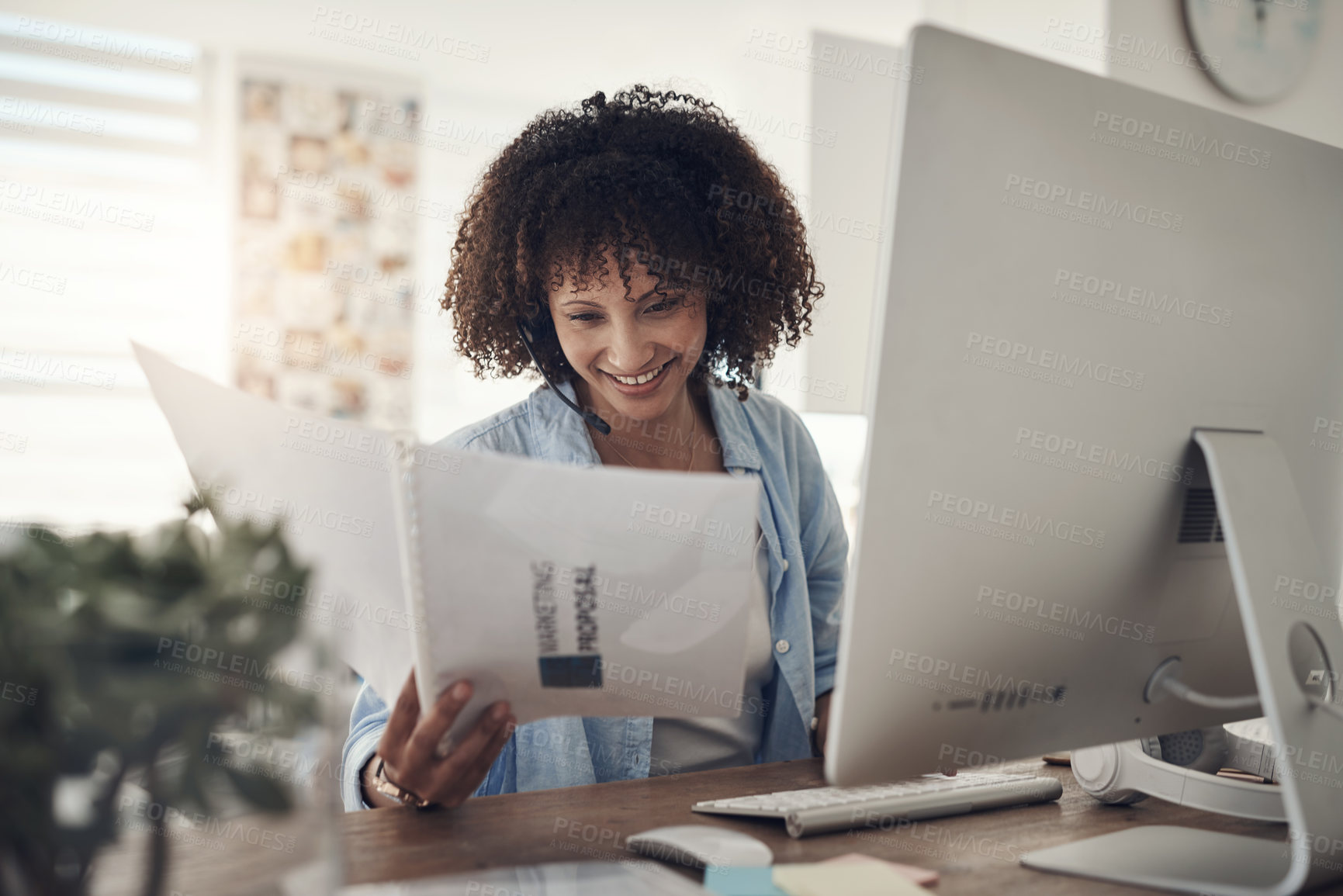 Buy stock photo Shot of an attractive young woman sitting alone at home and using her computer while reading paperwork