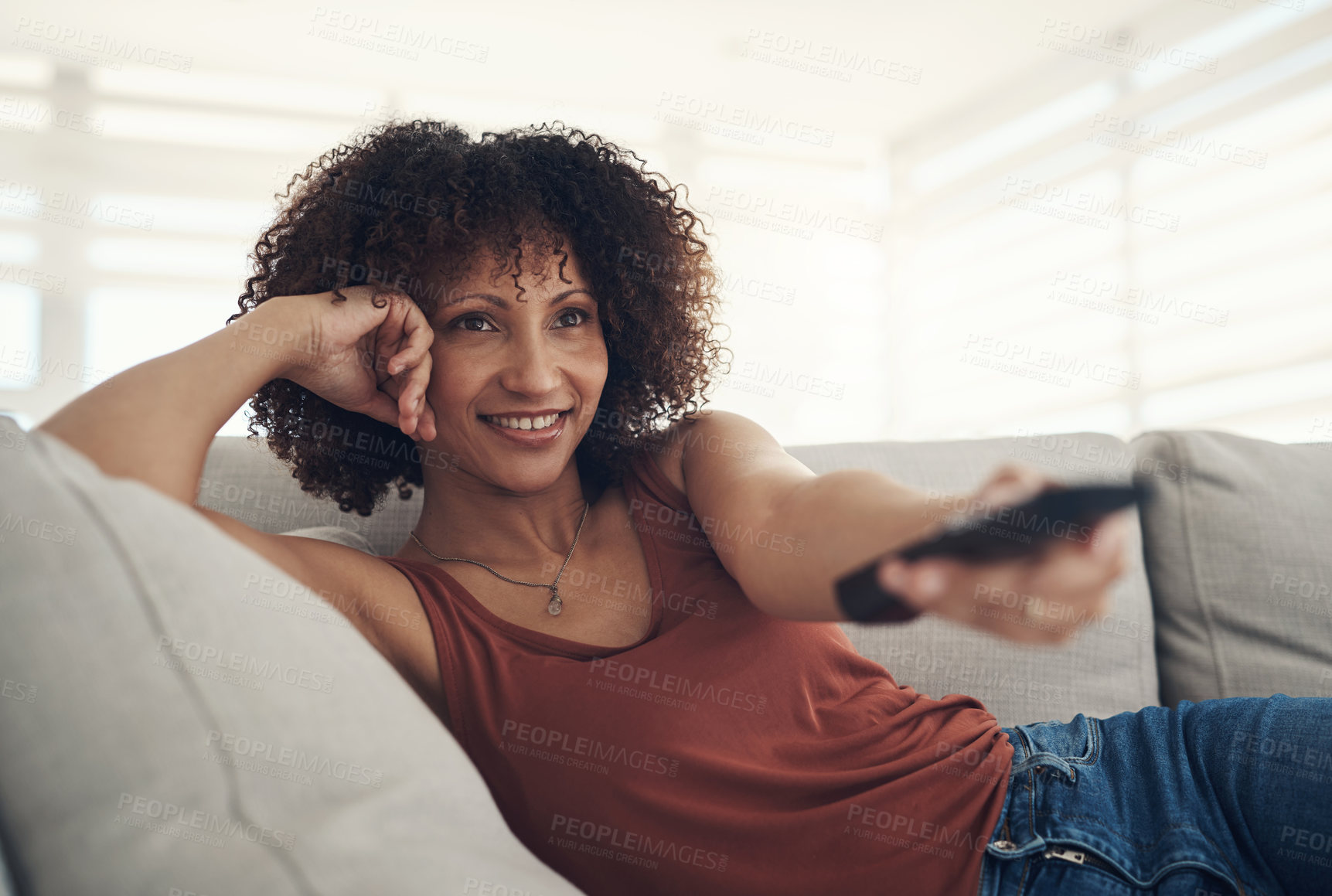 Buy stock photo Shot of an attractive young woman relaxing on the sofa in the living room at home and watching tv