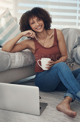 Buy stock photo Shot of an attractive young woman sitting on her living room floor and using her laptop while drinking coffee