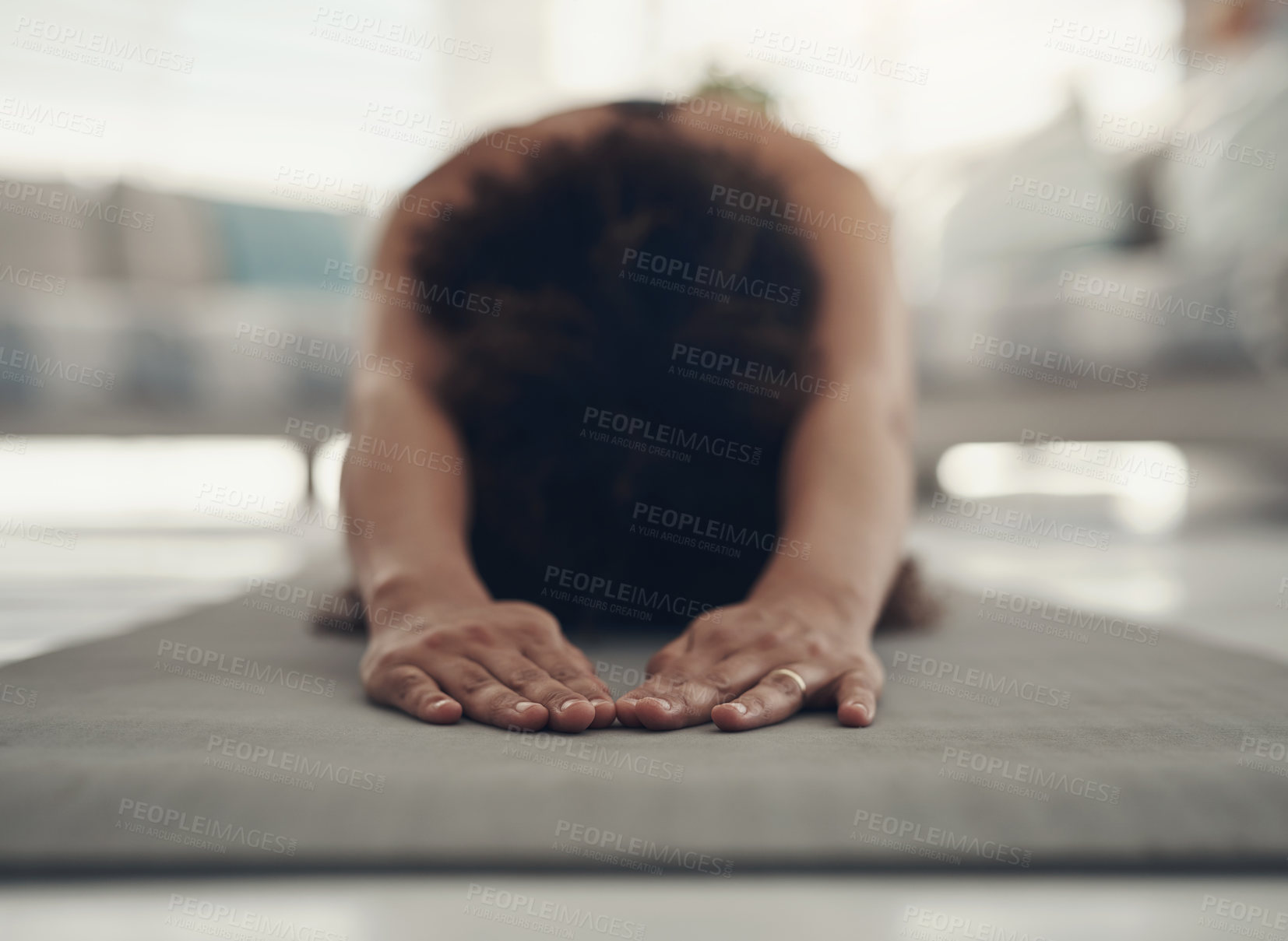 Buy stock photo Shot of an unrecognizable woman practising yoga in her living room and holding a child's pose