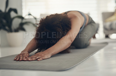 Buy stock photo Shot of an unrecognizable woman practising yoga in her living room and holding a child's pose