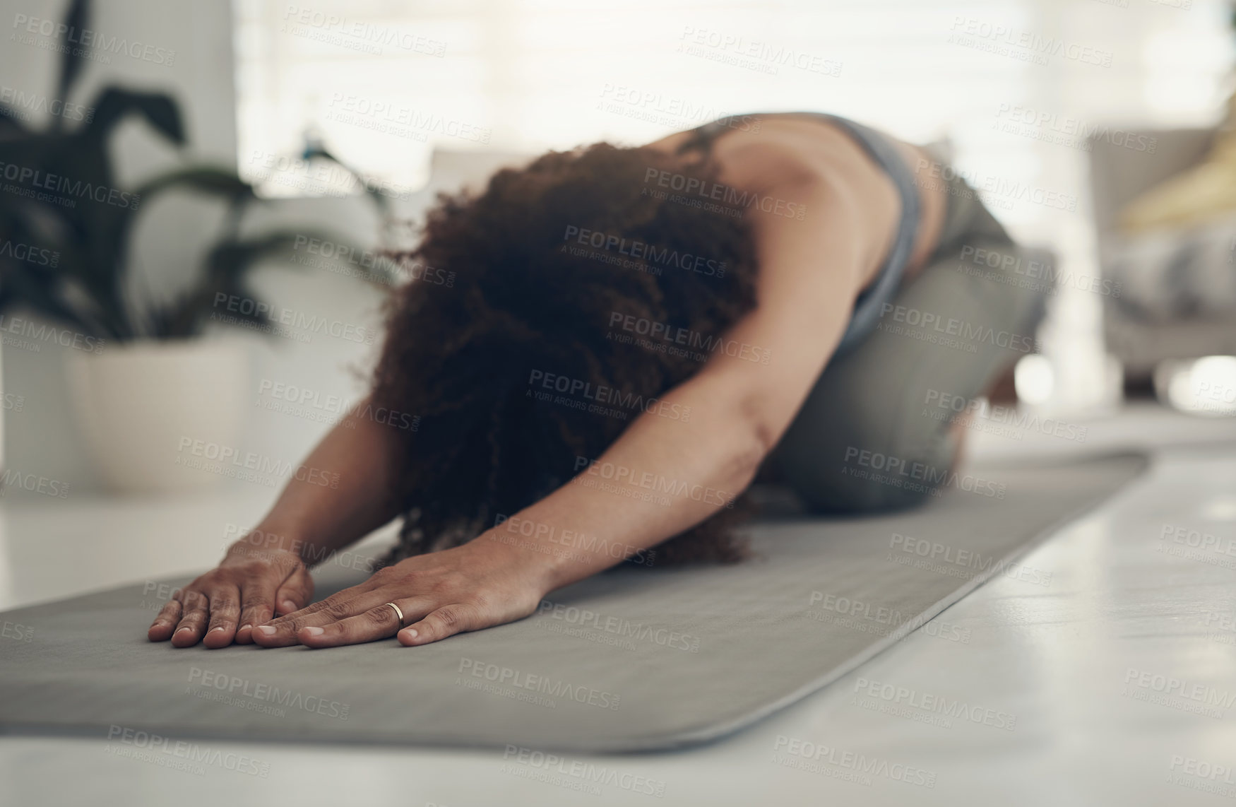 Buy stock photo Shot of an unrecognizable woman practising yoga in her living room and holding a child's pose