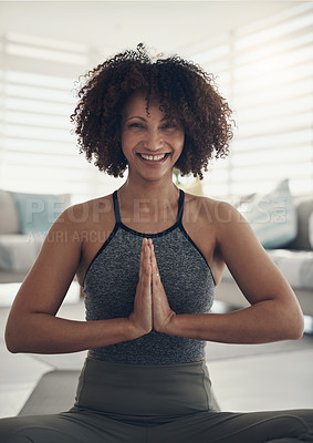 Buy stock photo Shot of an attractive young woman sitting alone in her living room and meditating