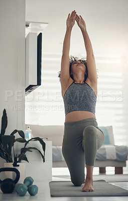 Buy stock photo Shot of an attractive young woman practising yoga in her living room