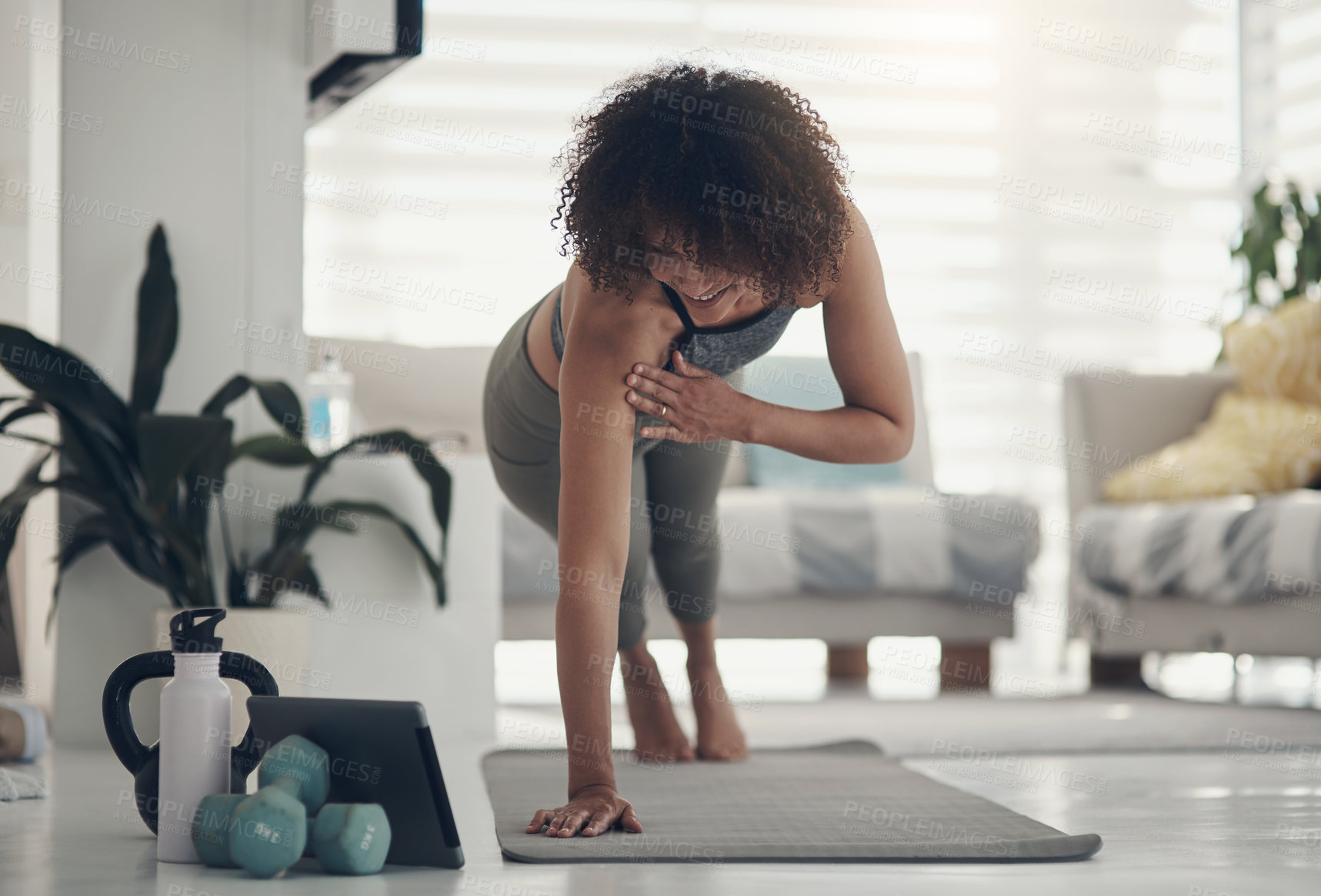 Buy stock photo Shot of an attractive young woman working out in her living room during the day