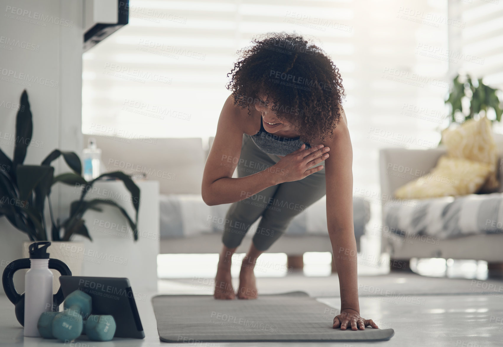 Buy stock photo Shot of an attractive young woman working out in her living room during the day