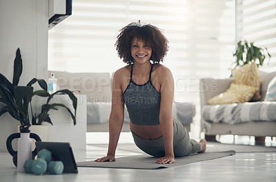 Buy stock photo Shot of an attractive young woman practising yoga in her living room and holding an upward facing dog pose