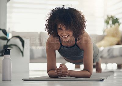 Buy stock photo Shot of an attractive young woman working out in her living room during the day