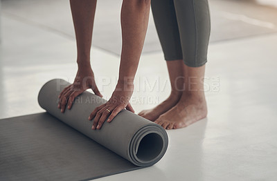 Buy stock photo Cropped shot of an unrecognizable woman rolling up her yoga mat after a practice session in her living room
