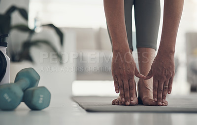 Buy stock photo Cropped shot of an unrecognizable woman practicing yoga at home and touching her toes