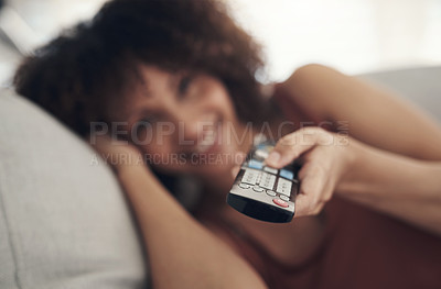 Buy stock photo Defocused shot of a young woman relaxing on the sofa in the living room at home and watching tv