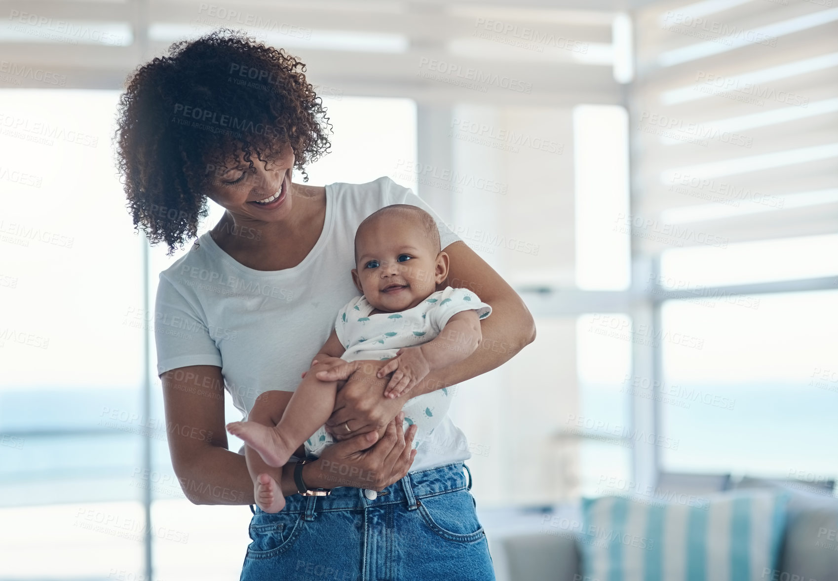 Buy stock photo Shot of a young woman carrying her adorable baby girl at home