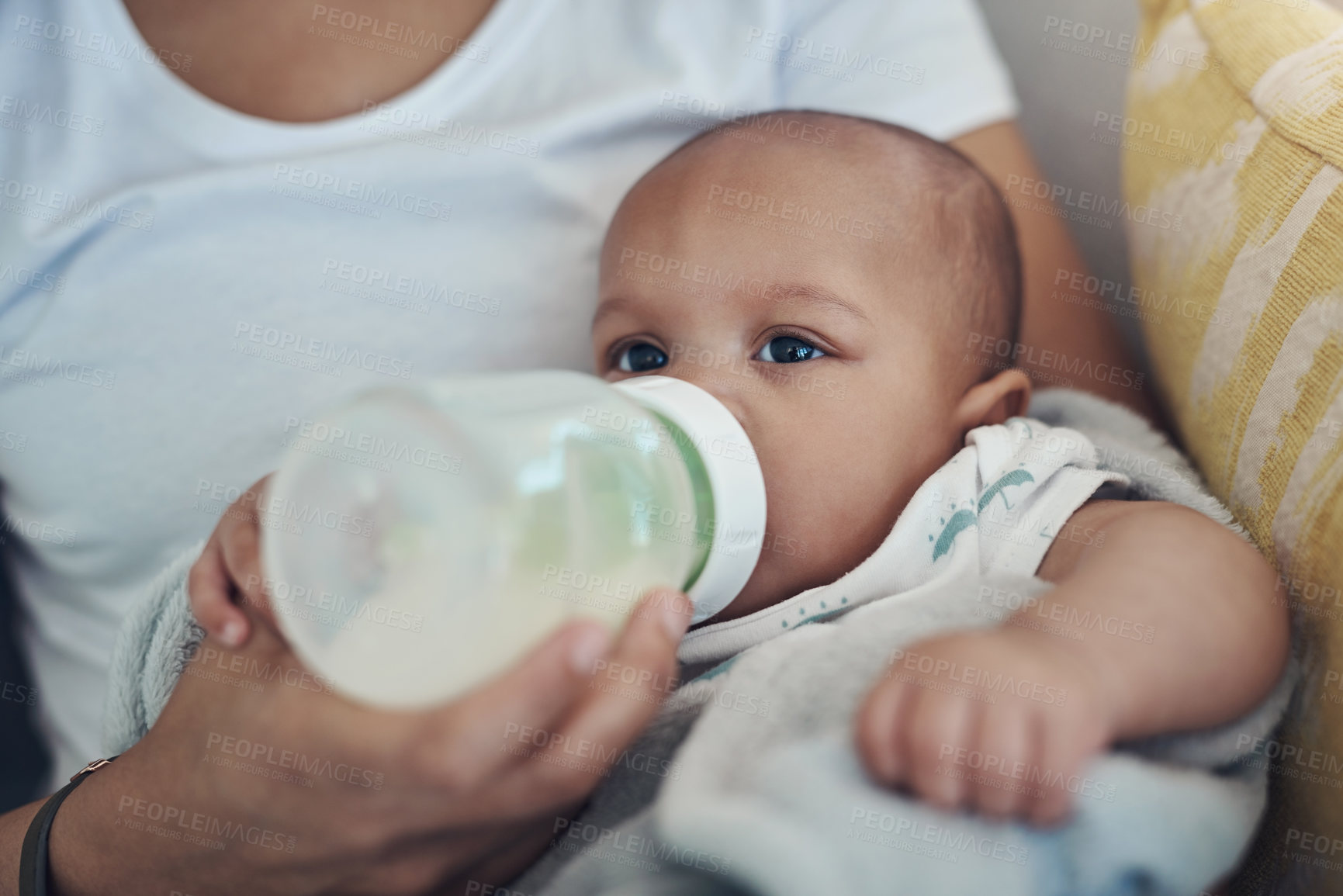 Buy stock photo Shot of an adorable baby girl being bottle fed by her mother on the sofa at home