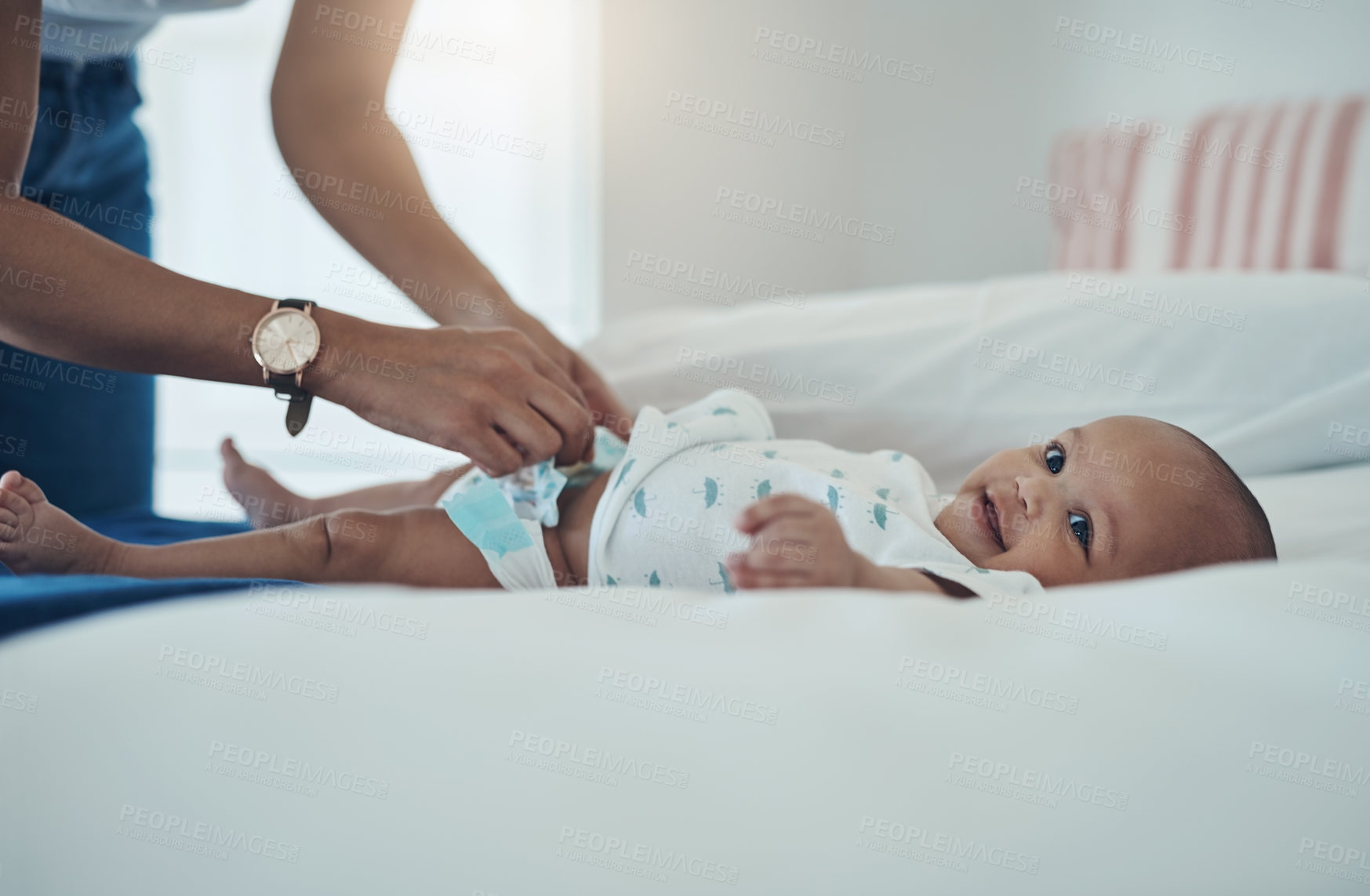 Buy stock photo Shot of a woman changing her adorable baby girl’s diaper on the bed at home