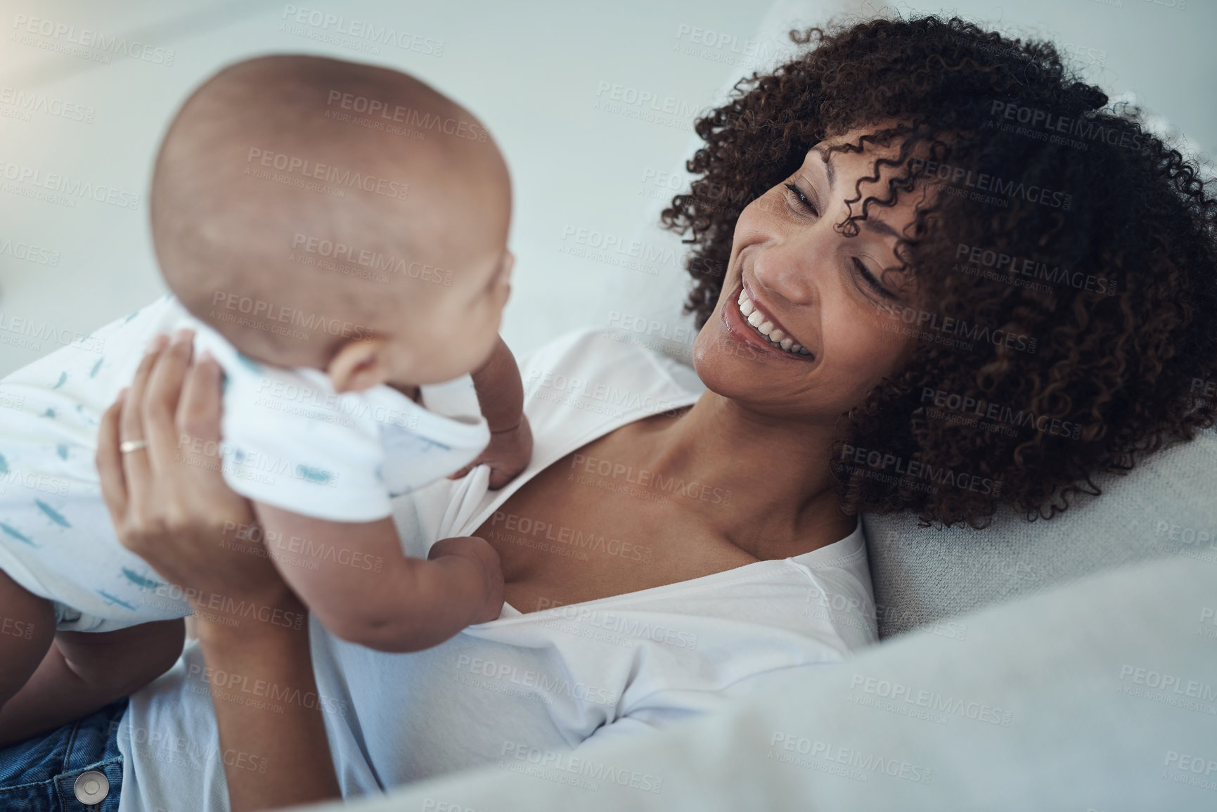 Buy stock photo Shot of a young woman relaxing with her adorable baby girl on the sofa at home