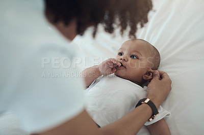 Buy stock photo Shot of a mother touching her adorable baby girl’s ear on the bed at home