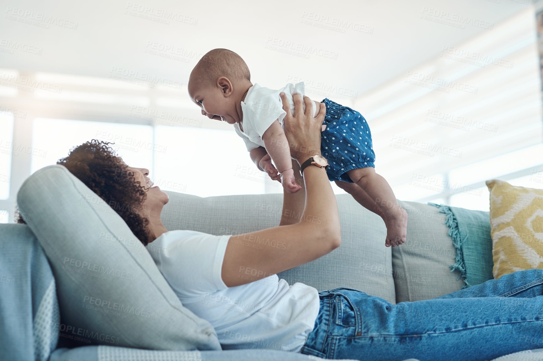 Buy stock photo Shot of a young woman relaxing with her adorable baby girl on the sofa at home