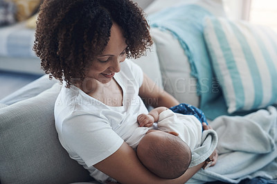 Buy stock photo Shot of a young woman breastfeeding her adorable baby girl on the sofa at home