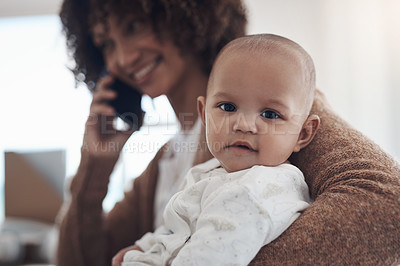 Buy stock photo Shot of a young woman using a smartphone while caring for her adorable baby girl at home