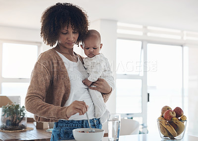 Buy stock photo Shot of a young woman preparing a meal for her adorable baby girl at home