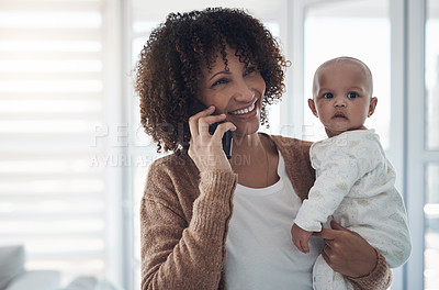 Buy stock photo Shot of a young woman using a smartphone while carrying her adorable baby girl at home
