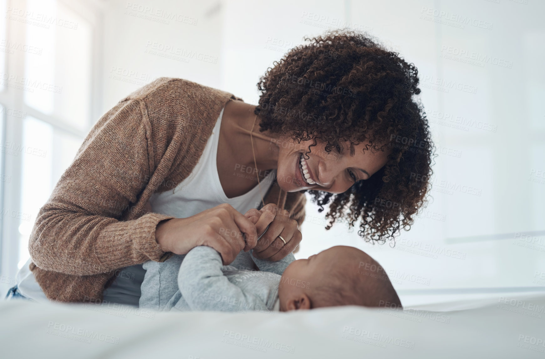 Buy stock photo Shot of a young woman playing with her adorable baby girl on the bed at home