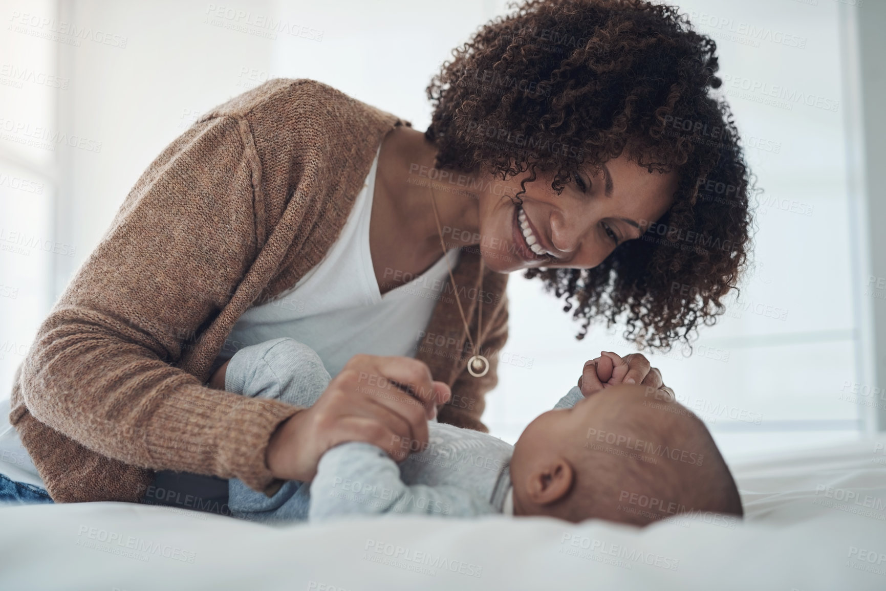 Buy stock photo Shot of a young woman playing with her adorable baby girl on the bed at home