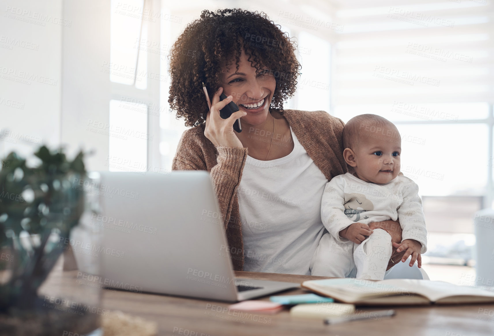 Buy stock photo Shot of a young woman using a smartphone and laptop while caring for her adorable baby girl at home